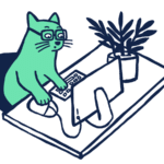 A cat with glasses sitting at the desk with a computer mouse, keyboard, monitor and a plant beside it